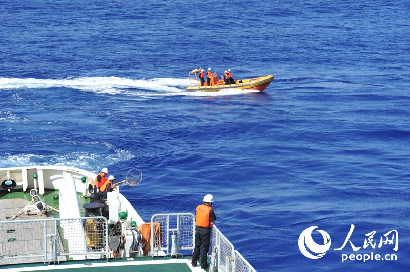 4月1日，“海巡01”在澳方今日公布的重點搜尋片區進行疑似物打撈、排除。圖為海巡01船載高速救生艇協同打撈組工作人員在后甲板等待打撈疑似漂浮物。張馳攝