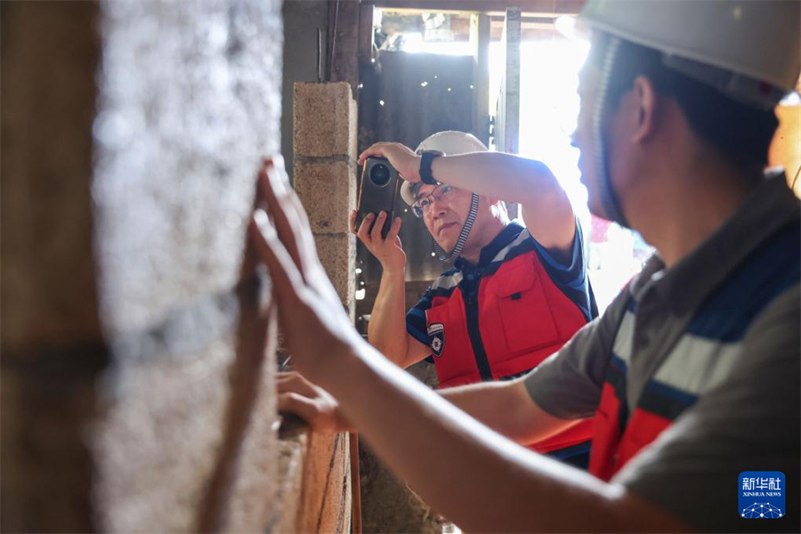 1月1日，在瓦努阿圖維拉港，中國地震局工程力學研究所研究員戴君武（左）在一處房屋內記錄受損情況。新華社記者 龍雷 攝